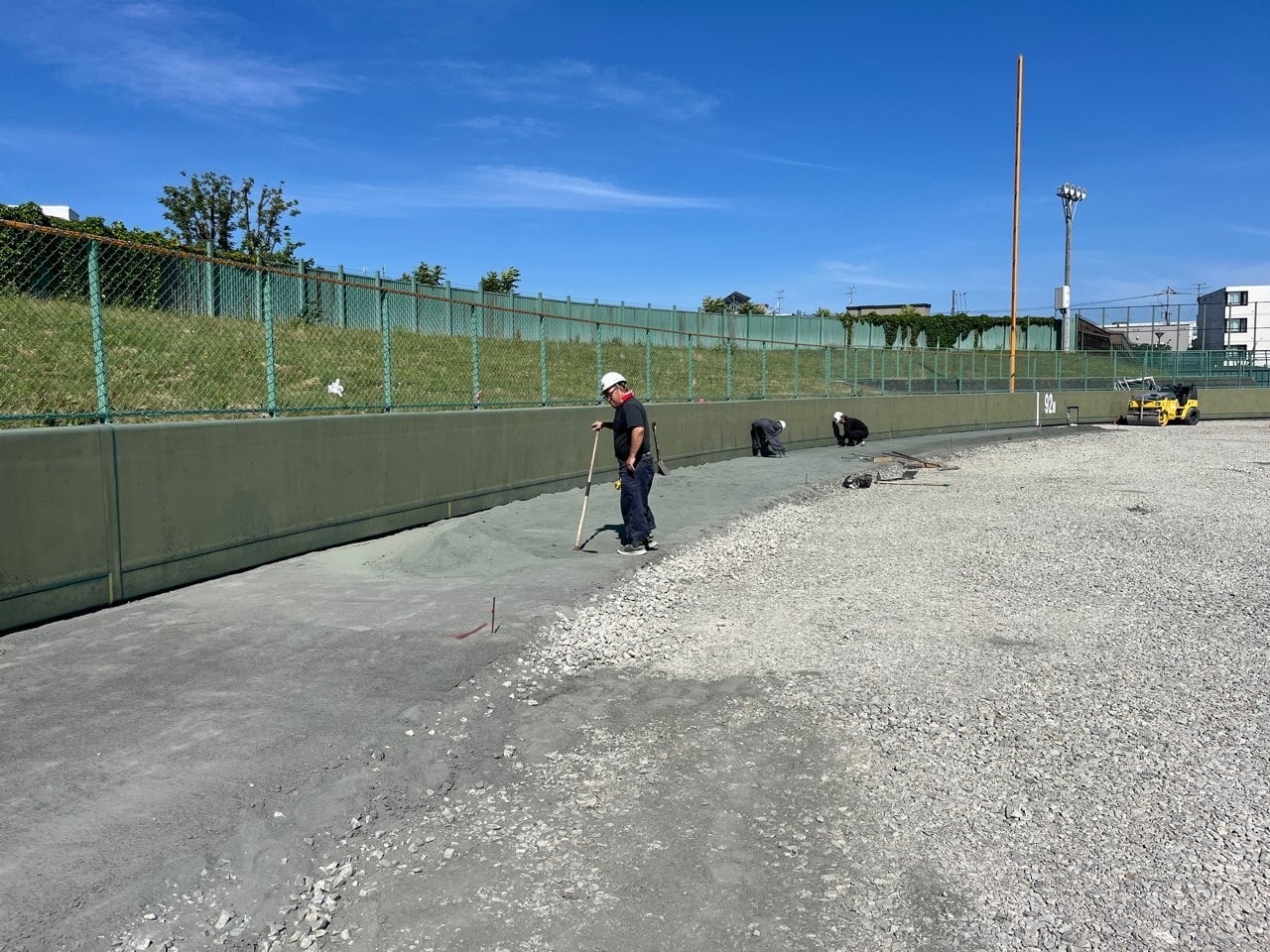 外野ではウォーニングゾーンを施工中。グリーンダストを敷均しています。