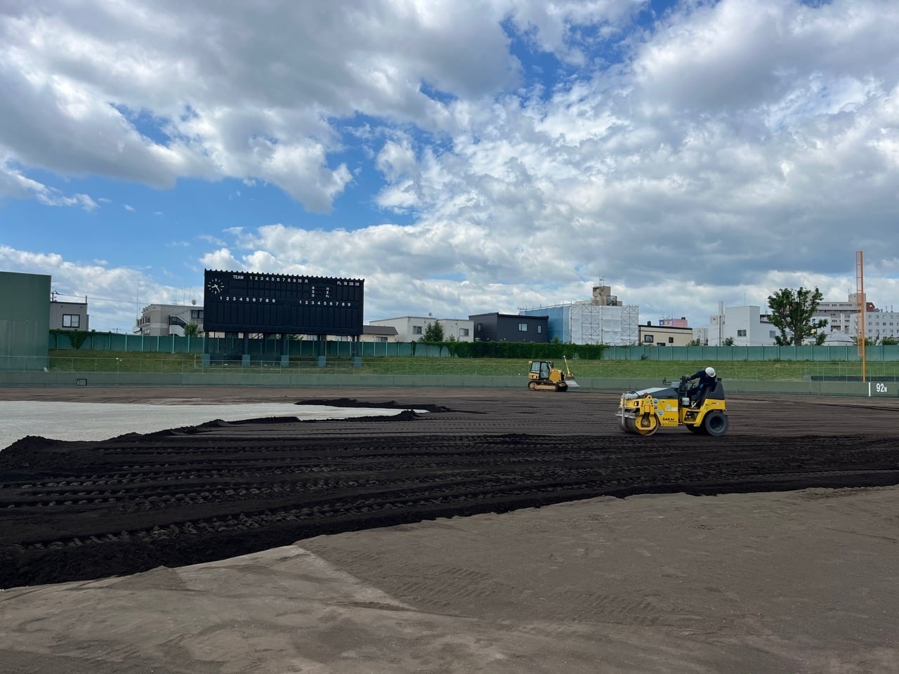 北海道らしくない厚さの中、外野黒土敷均しを行っています。熱中症対策として時間を決めて交代しながら作業を行っています